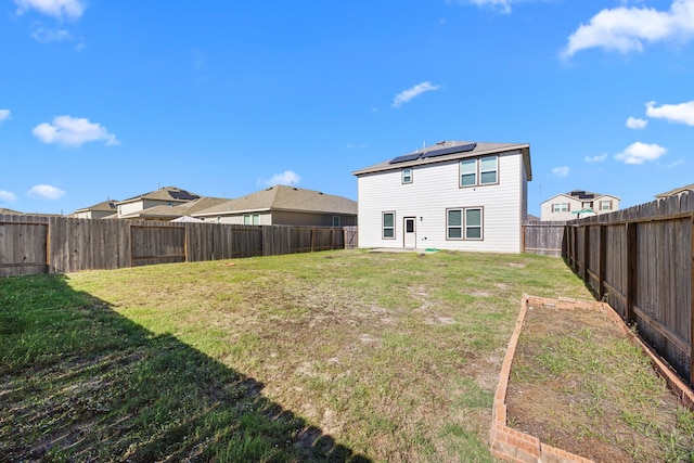 back of property featuring a lawn and solar panels