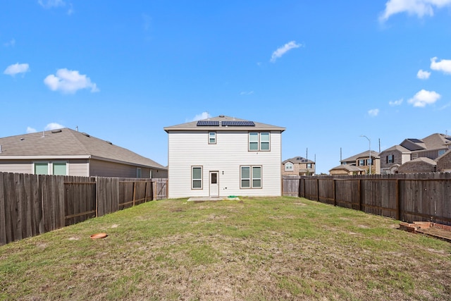 rear view of property with a lawn and solar panels