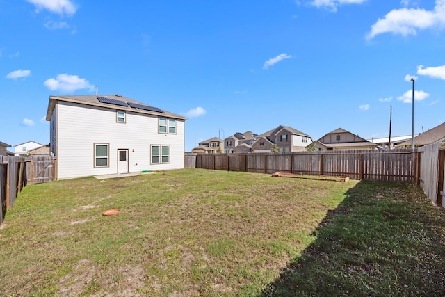 back of property featuring a lawn and solar panels