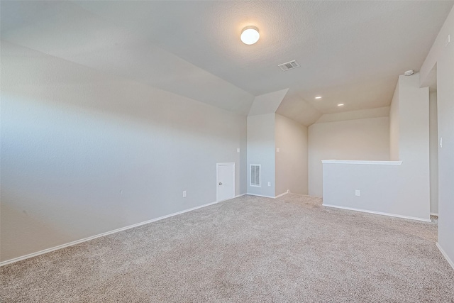 unfurnished room featuring a textured ceiling, carpet floors, and vaulted ceiling