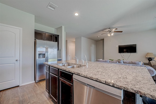 kitchen featuring appliances with stainless steel finishes, a kitchen island with sink, sink, light wood-type flooring, and dark brown cabinets