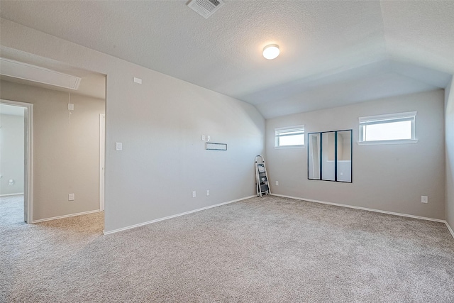 empty room featuring light colored carpet, a textured ceiling, and lofted ceiling