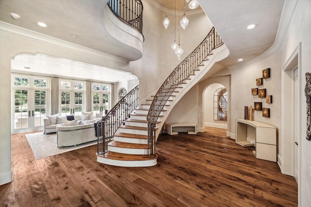 stairs featuring hardwood / wood-style flooring, a high ceiling, ornamental molding, and french doors