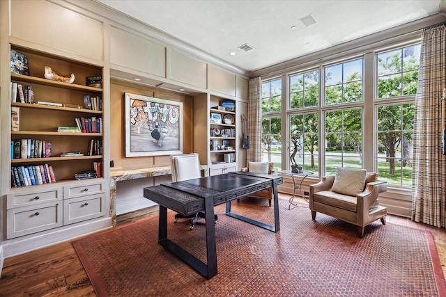 home office with crown molding, built in features, wood-type flooring, and built in desk