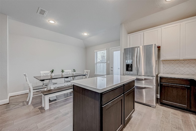 kitchen featuring dark brown cabinetry, a kitchen island, white cabinetry, backsplash, and stainless steel fridge with ice dispenser