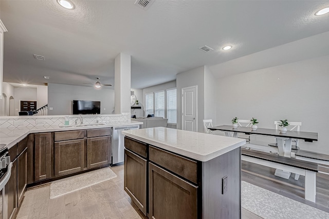 kitchen with appliances with stainless steel finishes, sink, backsplash, a center island, and light hardwood / wood-style floors