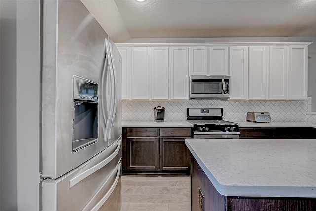 kitchen featuring dark brown cabinets, white cabinets, light wood-type flooring, and stainless steel appliances