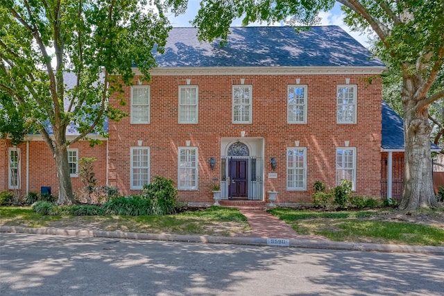 view of front of home featuring a shingled roof and brick siding