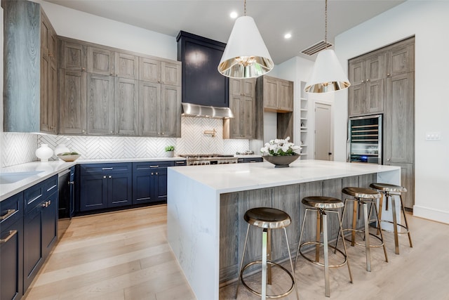 2231 Colquitt St, Houston, TX 77098 - kitchen with wine cooler, light wood finished floors, premium range hood, decorative backsplash, and recessed lighting