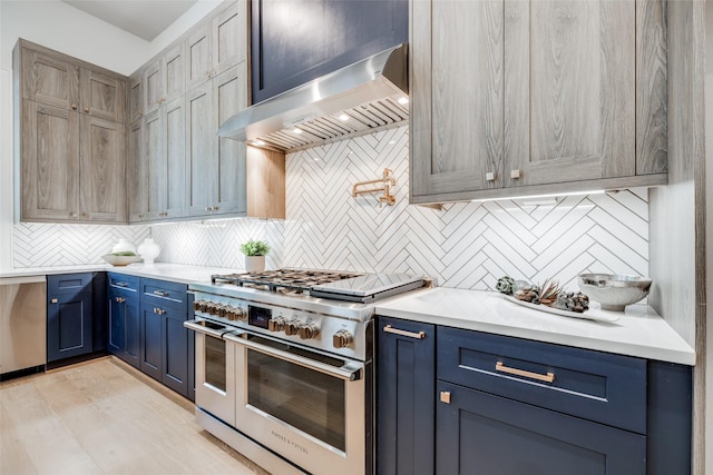 2231 Colquitt St, Houston, TX 77098 - kitchen with appliances with stainless steel finishes, wall chimney range hood, blue cabinetry, backsplash, and light countertops