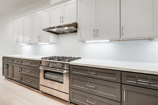 kitchen with high end stainless steel range, white cabinets, gray cabinetry, light hardwood / wood-style floors, and decorative backsplash