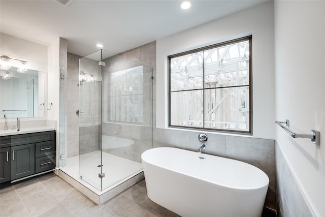 bathroom featuring plus walk in shower, tile walls, tile patterned flooring, and vanity