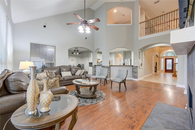 living room with hardwood / wood-style flooring, a high ceiling, and ceiling fan