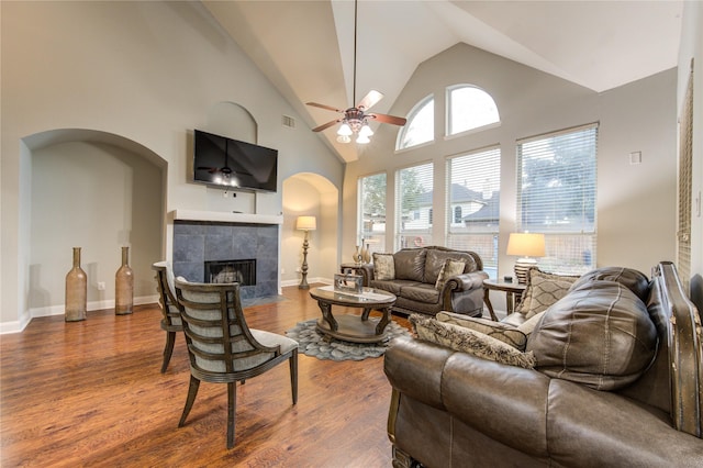 living room featuring a tile fireplace, hardwood / wood-style flooring, high vaulted ceiling, and ceiling fan