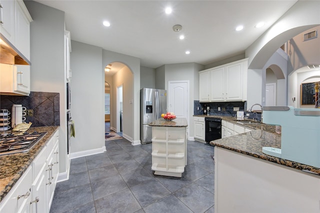 kitchen with sink, white cabinets, dark stone countertops, and stainless steel appliances