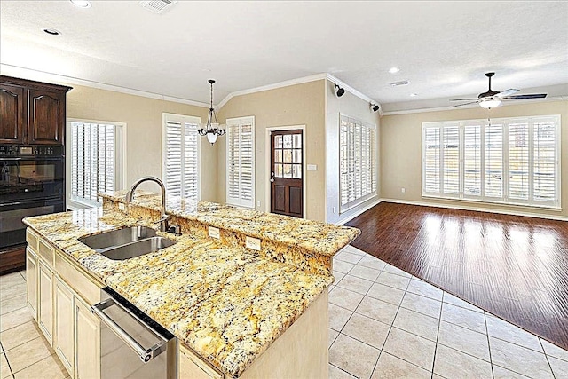 kitchen featuring sink, light tile patterned floors, ornamental molding, and an island with sink