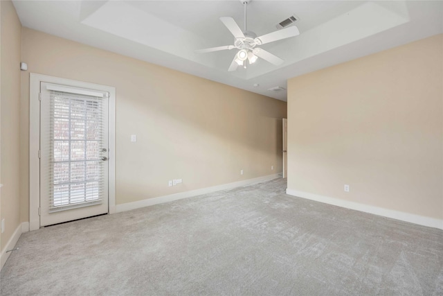 carpeted spare room featuring a raised ceiling and ceiling fan