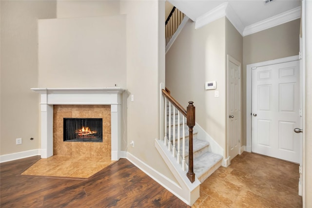 stairway with hardwood / wood-style flooring, crown molding, and a fireplace