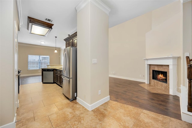 kitchen with hanging light fixtures, dark brown cabinets, light tile patterned floors, appliances with stainless steel finishes, and a tile fireplace