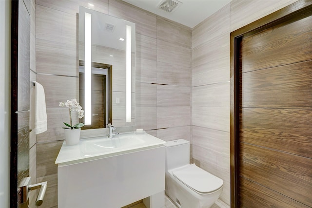 bathroom with tile walls, vanity, and toilet