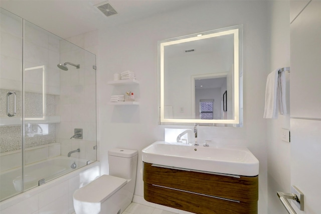 full bathroom with bath / shower combo with glass door, vanity, and toilet