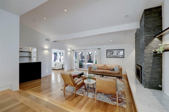 living room featuring a stone fireplace, light hardwood / wood-style flooring, and lofted ceiling with beams