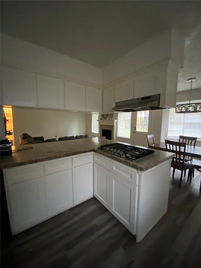 kitchen with dark wood-type flooring, white cabinetry, stainless steel gas stovetop, and kitchen peninsula