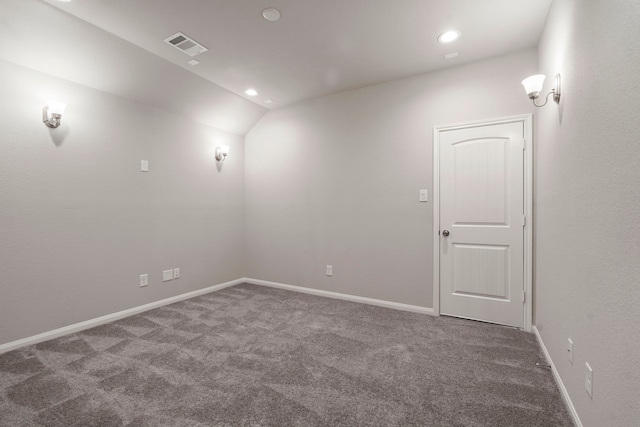 empty room with vaulted ceiling and dark carpet