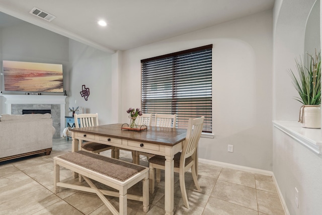 dining area with a tiled fireplace and light tile patterned floors