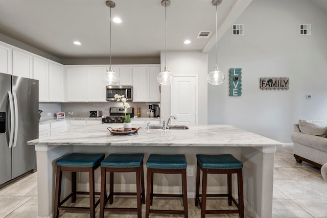 kitchen with white cabinetry, sink, stainless steel appliances, and a large island with sink