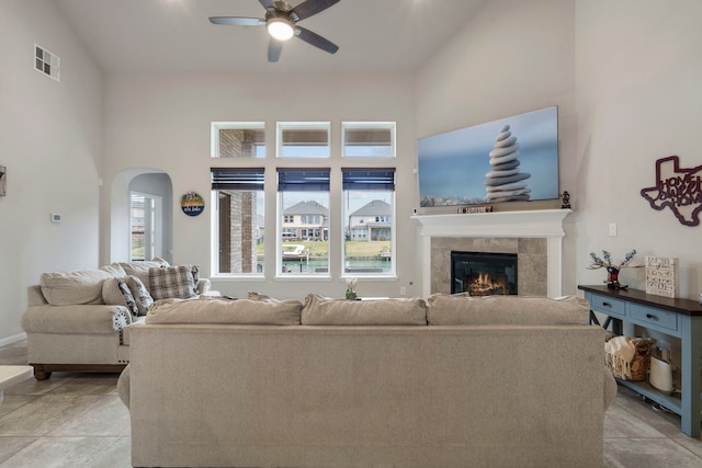 living room with lofted ceiling, light tile patterned floors, a tile fireplace, and ceiling fan