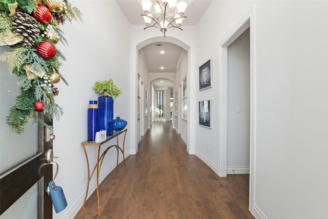 hall with a chandelier and dark wood-type flooring