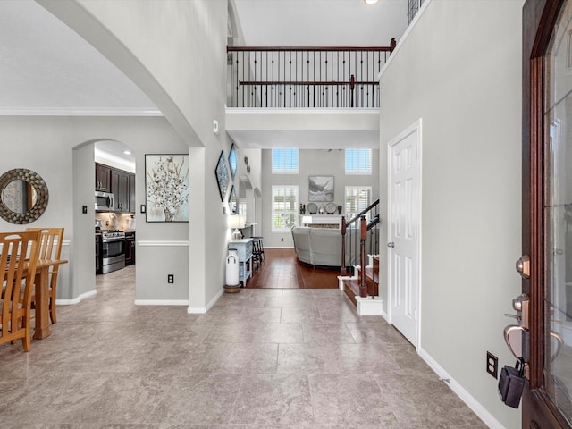 entryway featuring a towering ceiling and crown molding