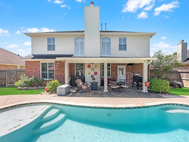 back of house featuring a fenced in pool and a patio