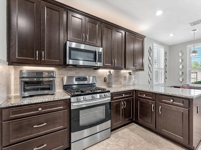 kitchen featuring hanging light fixtures, decorative backsplash, dark brown cabinetry, kitchen peninsula, and stainless steel appliances