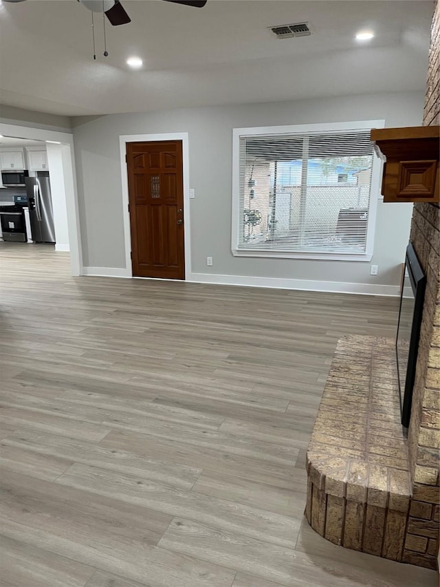 entryway featuring a brick fireplace, ceiling fan, and light hardwood / wood-style flooring