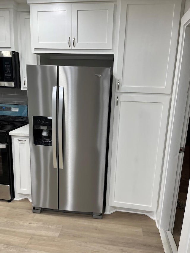 kitchen featuring white cabinetry, decorative backsplash, light hardwood / wood-style flooring, and stainless steel appliances