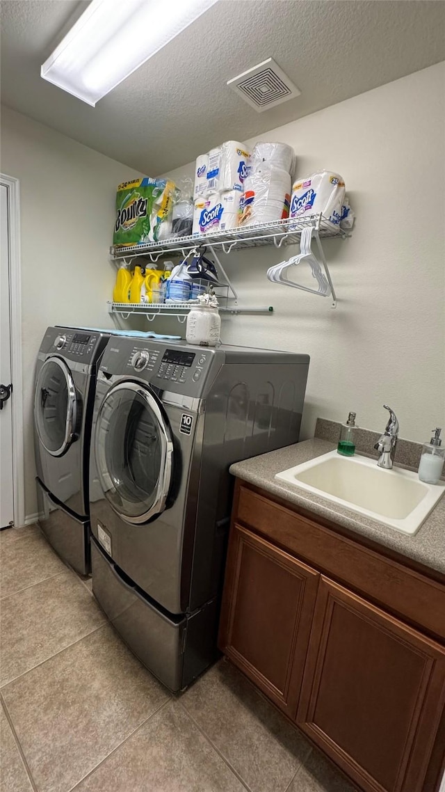 washroom featuring light tile patterned floors, sink, a textured ceiling, and washer and clothes dryer