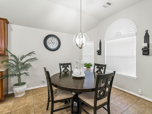 tiled dining area featuring an inviting chandelier and vaulted ceiling