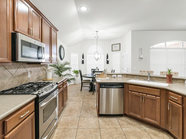 kitchen with lofted ceiling, sink, stainless steel appliances, tasteful backsplash, and decorative light fixtures