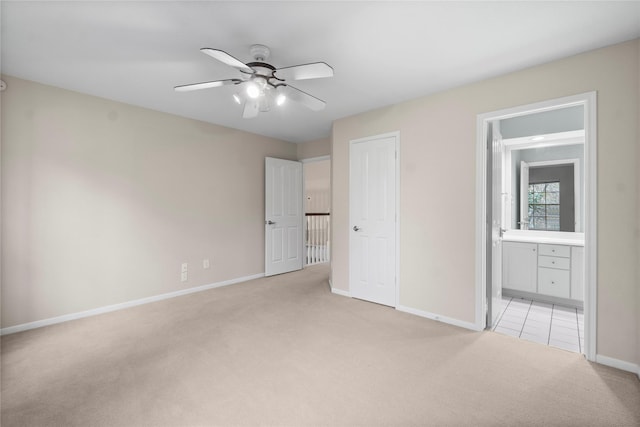 unfurnished bedroom with light colored carpet, a closet, ceiling fan, and ensuite bathroom