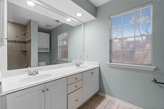 bathroom with vanity, toilet, tile patterned flooring, and a tile shower