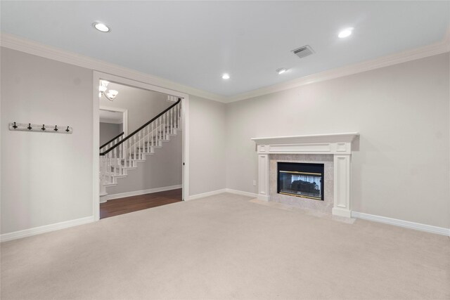 unfurnished living room featuring ornamental molding, carpet flooring, and a tiled fireplace