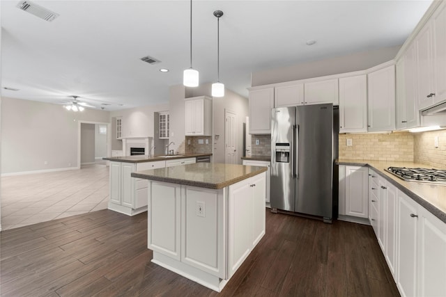 kitchen with hanging light fixtures, appliances with stainless steel finishes, a kitchen island, ceiling fan, and white cabinets