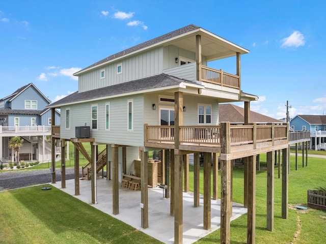 rear view of house with a balcony, a lawn, a patio area, cooling unit, and a deck