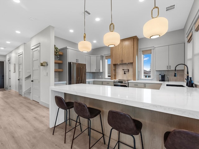 kitchen featuring decorative light fixtures, sink, kitchen peninsula, and stainless steel appliances