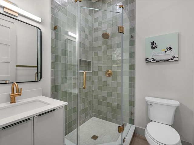 bathroom featuring vanity, toilet, and a shower with door