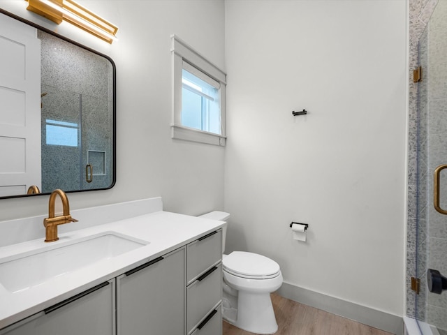 bathroom with vanity, toilet, hardwood / wood-style floors, and a shower with door