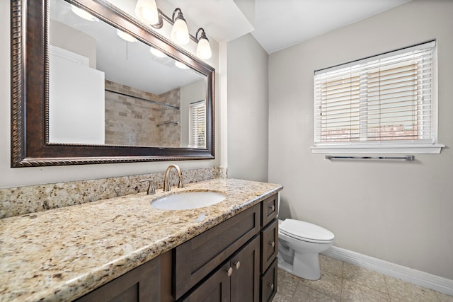 bathroom with toilet, vanity, and tiled shower