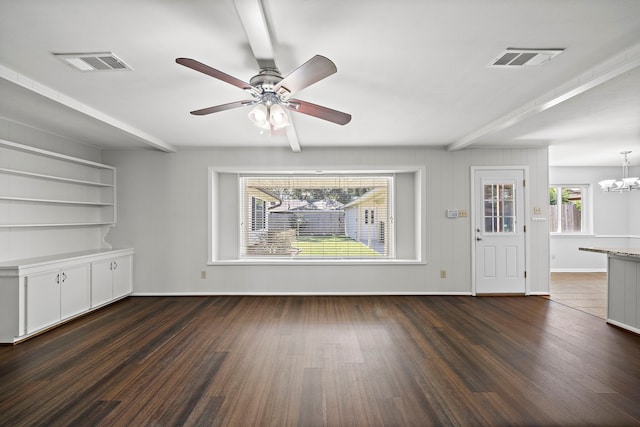 unfurnished living room with ceiling fan with notable chandelier, beamed ceiling, and dark hardwood / wood-style flooring